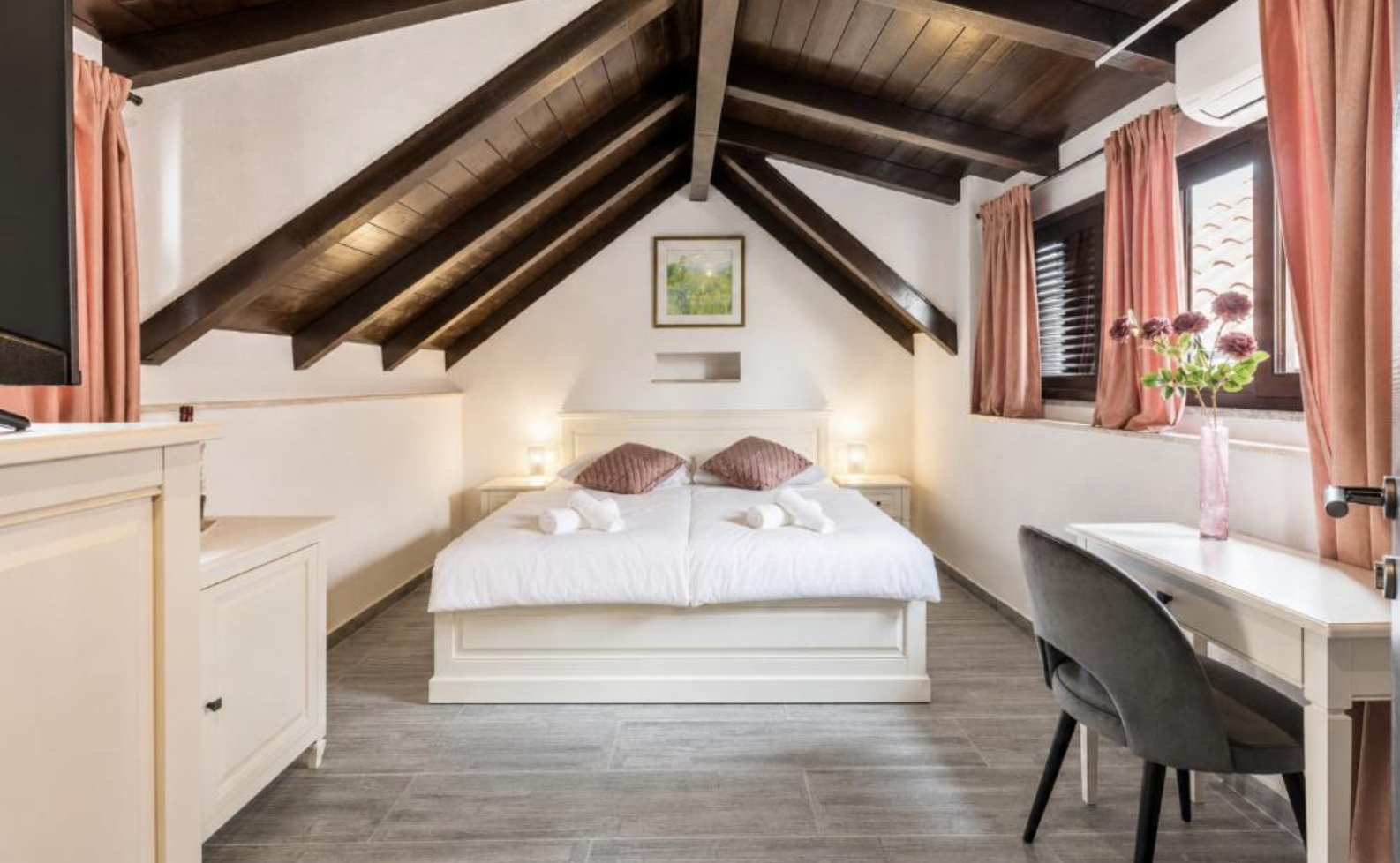 Attic room with exposed timber roof beams and a desk